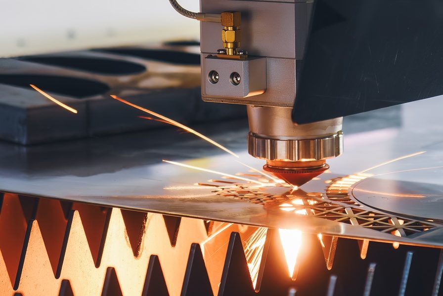 CNC-Laser Schneidvorgang mit Funken auf Metalloberfläche.